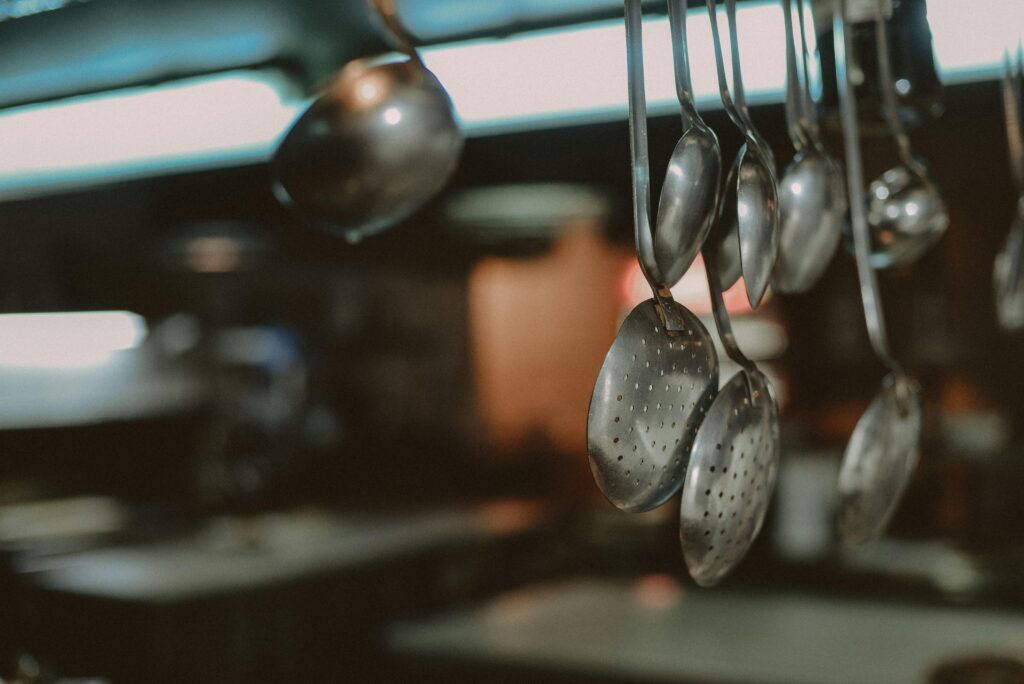 Close-up of hanging metal spoons and ladles in a kitchen, blurred background
